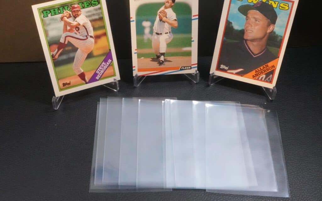 3 baseball cards with card sleeves spread out in front of them