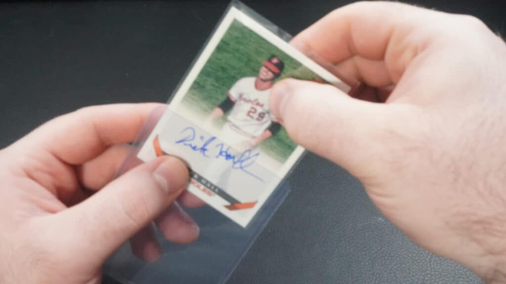 pushing a sleeved baseball card into a toploader